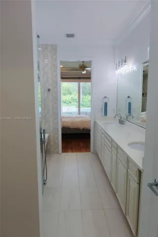 Bathroom featuring dual-sink vanity with light-tone cabinetry, quartz countertop, full-width wall mirror, and large-format tile flooring
