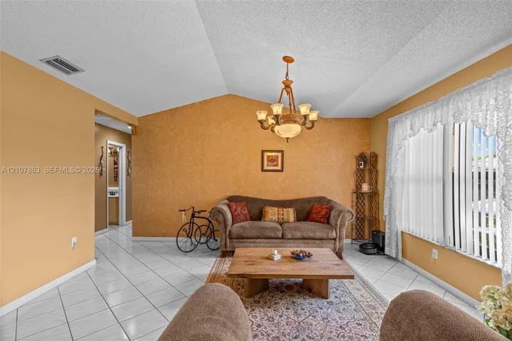Vaulted ceilings featuring a central multi-arm chandelier and diagonal-set ceramic tile flooring
