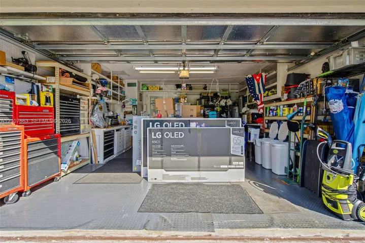 Garage space featuring built-in industrial shelving, integrated workbench cabinetry, textured floor matting, and overhead fluorescent lighting
