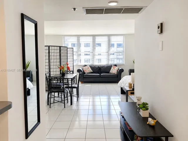 Bright, open-concept interior featuring white ceramic tile flooring and floor-to-ceiling windows with horizontal blinds