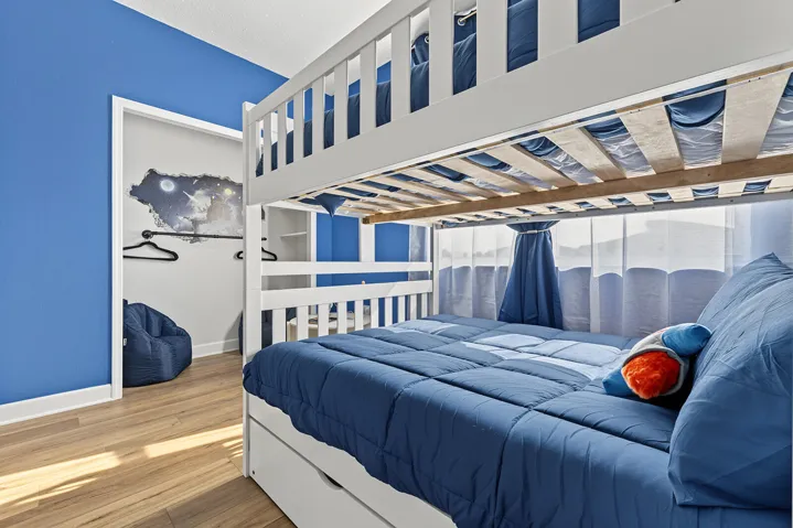 Room featuring blue-toned walls, vinyl wood-finish flooring, and a walk-in closet with built-in shelving