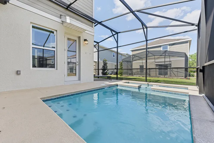 Screen-enclosed swimming pool featuring a tiled waterline, built-in steps, and a concrete deck surround