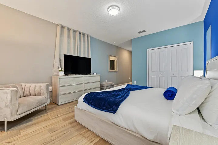 Bedroom featuring vinyl wood-finish flooring, dual-panel closet doors, and a flush-mount ceiling light