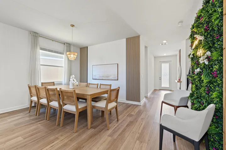 Dining area featuring vinyl wood-finish flooring, vertical slat wall paneling, and a tiered drum pendant light fixture