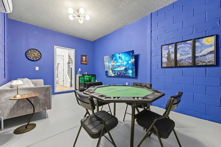 Interior space featuring Card table, Large Screen TV, Arcade games, wall-mounted ductless climate control unit, overhead globe chandelier, and solid flooring.