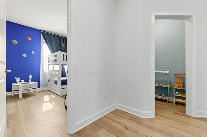 Room featuring vinyl wood-finish flooring, accent wall, and a recessed alcove