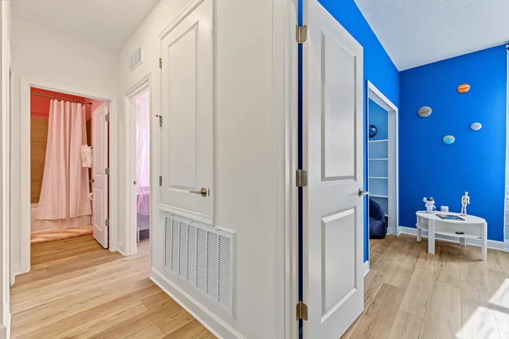Hallway featuring vinyl wood-finish flooring, two-panel interior doors, and built-in shelving