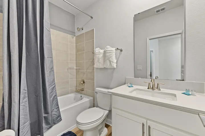 Bathroom featuring a vanity with an integrated rectangular sink, stone-finish countertop, full-height wall mirror, and a shower-tub combination with tiled surround.