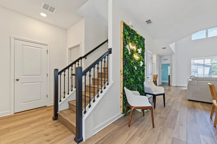 Staircase featuring wood-finish treads and a matte black metal railing, vinyl wood-finish flooring, and a decorative living-wall installation