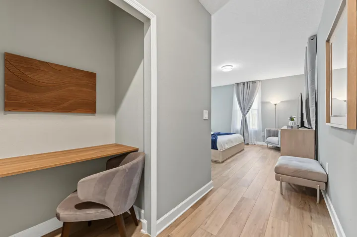 Built-in wood-finish desk featuring a recessed alcove, wall-mounted wood-finish wall art, and vinyl wood-finish flooring