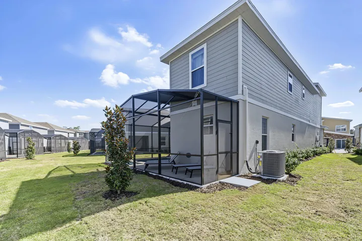 Two-story exterior featuring lap siding, stucco finish, a screened-in lanai, and an expansive lawn area