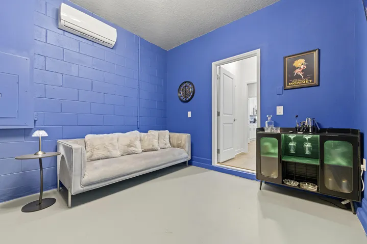 Interior space featuring Card table, Large Screen TV, Arcade games, wall-mounted ductless climate control unit, overhead globe chandelier, and solid flooring.