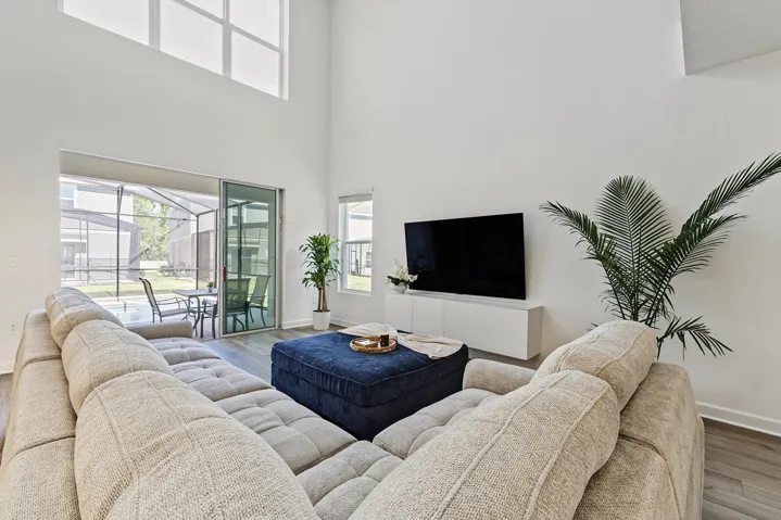 Living area featuring vaulted ceilings, floor-to-ceiling windows, vinyl wood-finish flooring, sliding glass door, and a wall-mounted built-in cabinet