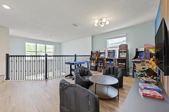 Open-concept area featuring Vinyl wood-finish flooring, matte black metal spindle railing, large windows, and multi-arm geometric ceiling lighting