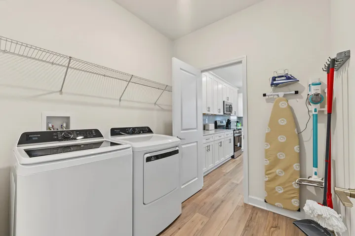 Laundry area featuring vinyl wood-finish flooring, white cabinetry, a wall-mounted wire shelving system, and a recessed water hookup