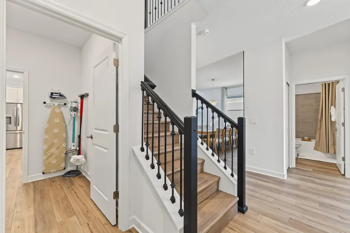 Staircase featuring wood-finish treads and black metal balusters, complemented by vinyl wood-finish flooring throughout