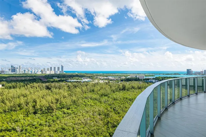 Curved balcony with tile flooring and a glass panel railing