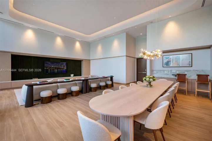 High-ceiling interior featuring recessed tray lighting, wood-finish flooring, a built-in entertainment niche, and a custom bar area with stone-finish surfacing and integrated​​‌​​​​‌​​‌‌​‌‌​​​‌‌​‌​‌​‌​​​‌​​ lighting
