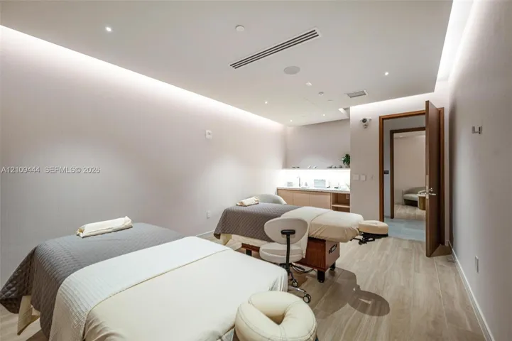 Interior room featuring wood-finish flooring, recessed ceiling lighting with perimeter cove illumination, and built-in cabinetry with integrated under-counter lighting