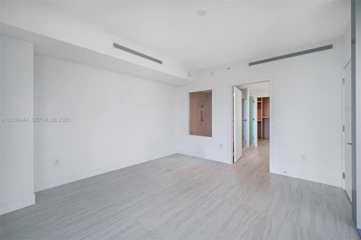 Neutral interior featuring wood-finish flooring, recessed ceiling linear diffusers, and a built-in recessed wall niche