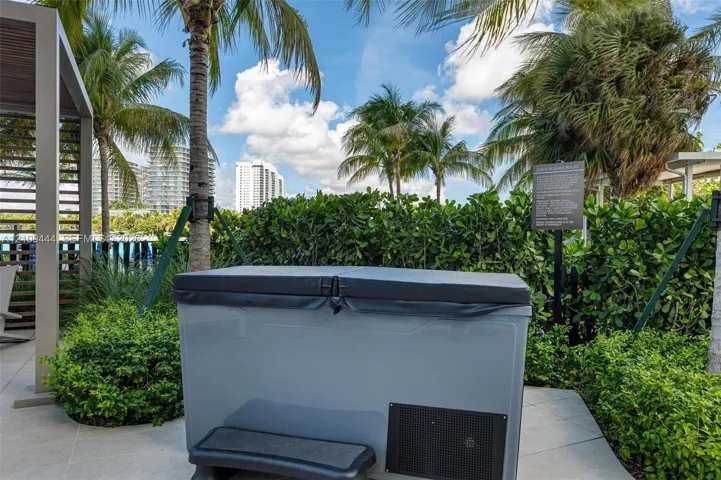 Outdoor hot tub featuring a hard-top cover and integrated step, set on a paved patio with a modern pergola and lush perimeter landscaping