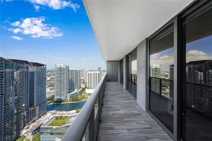 Expansive covered balcony featuring tile flooring, glass panel railings, and full-height sliding glass doors