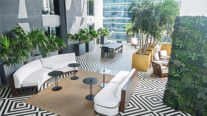 Outdoor terrace featuring a geometric tile floor, vertical living wall, and integrated built-in planters