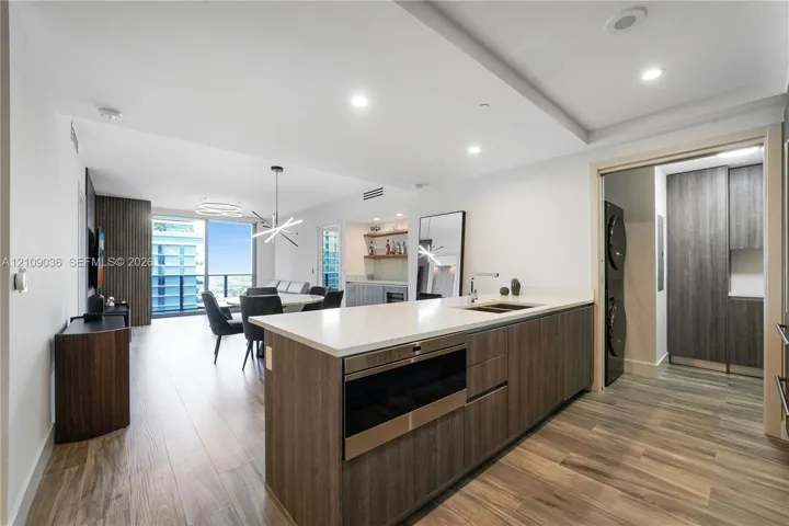 Kitchen island featuring white countertops, wood-finish cabinetry, built-in microwave, and recessed lighting