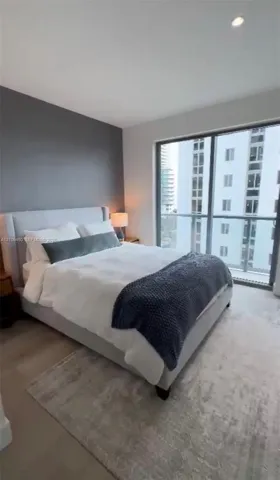 Floor-to-ceiling glass sliding doors, private balcony, accent wall, recessed ceiling lighting, and neutral-toned carpeting