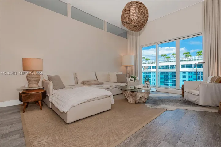 High ceilings featuring clerestory windows, wood-finish flooring, and large-format sliding glass doors with balcony access