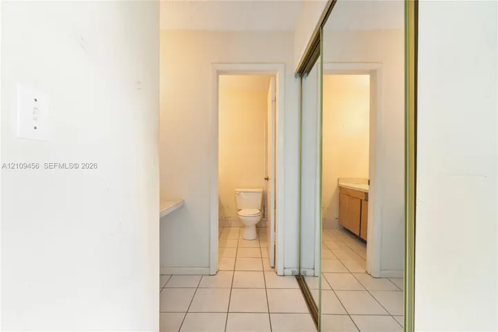 Floor-to-ceiling mirrored sliding closet doors, ceramic tile flooring, and integrated wall-mounted vanity counter