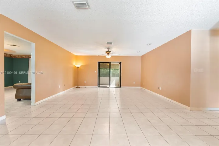 Neutral-toned ceramic tile flooring, ceiling fan with integrated lighting, and sliding glass patio door