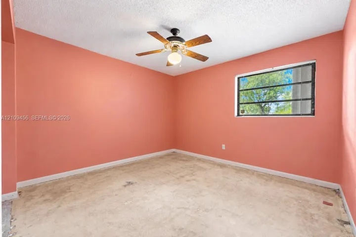 Room featuring a single-pane window, wood-finish blade ceiling fan with integrated light fixture, and textured ceiling finish