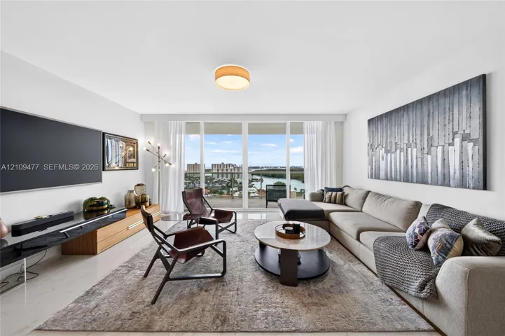 Living area featuring floor-to-ceiling glass panel doors, polished stone flooring, and built-in wall-mounted cabinetry