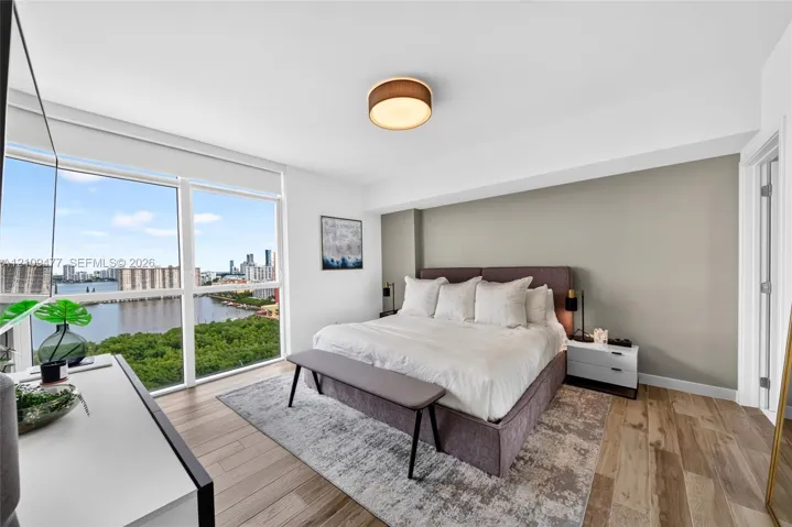 Floor-to-ceiling windows, wood-finish flooring, neutral accent wall, and circular drum-style flush mount lighting