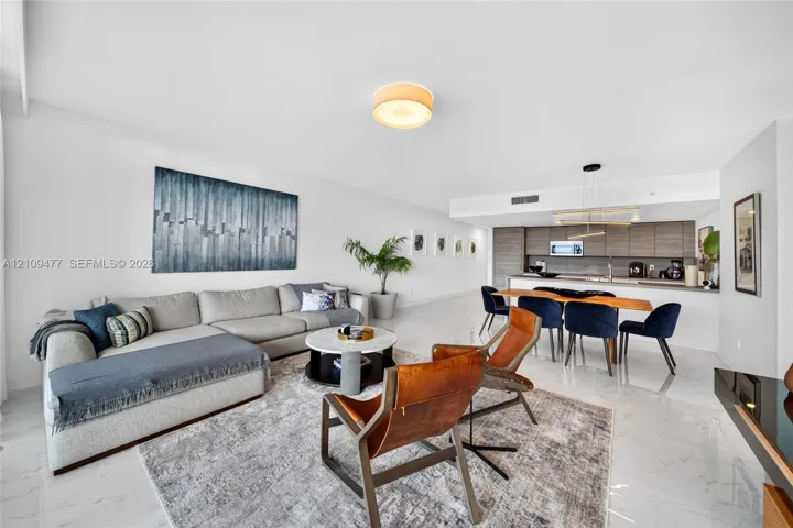 Open-concept living space featuring high-gloss tile flooring, flat-panel cabinetry, a kitchen island, and modern recessed and pendant lighting