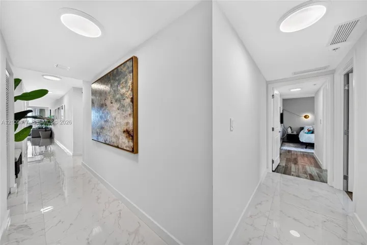 Hallway featuring polished stone-look tile flooring and recessed circular lighting