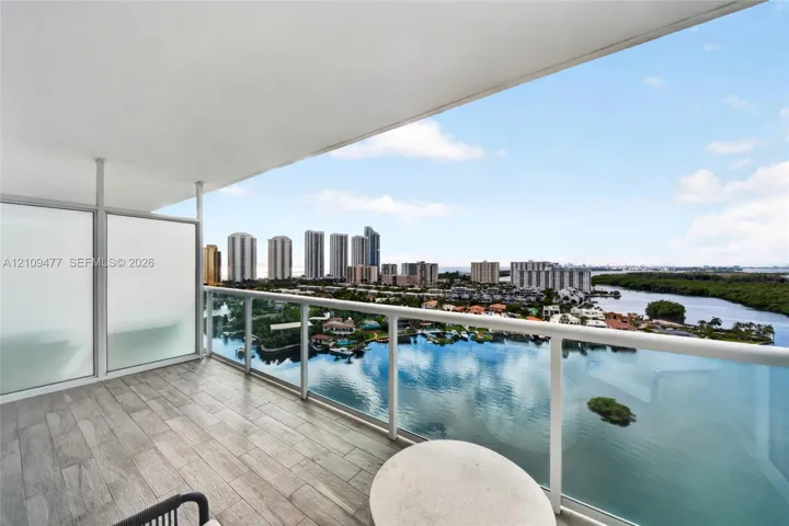 Covered balcony featuring wood-finish tile flooring, frosted glass privacy panels, and a sleek metal railing with a glass balustrade