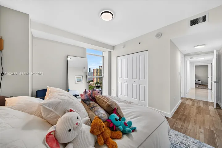 Floor-to-ceiling window, wood-finish flooring, and white double-door closet cabinetry