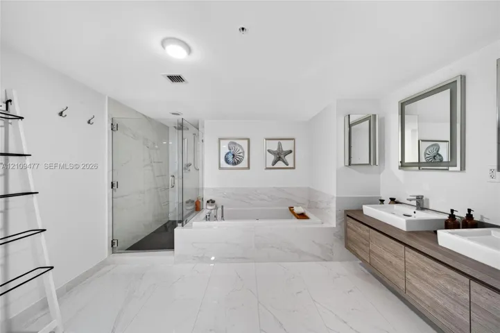 Floating wood-finish double vanity with rectangular vessel sinks, large-format tile flooring, built-in soaking tub with surround, and glass-enclosed shower