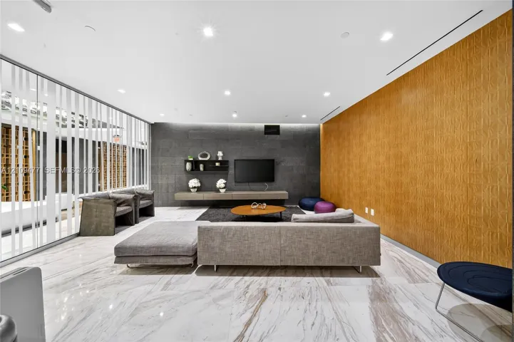 Large-format stone tile flooring, charcoal-toned stone accent wall, floor-to-ceiling glass wall, wood-finish wall paneling, and recessed lighting