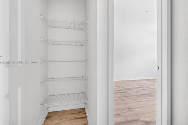 Storage closet featuring five tiers of white wire shelving and wood-finish flooring