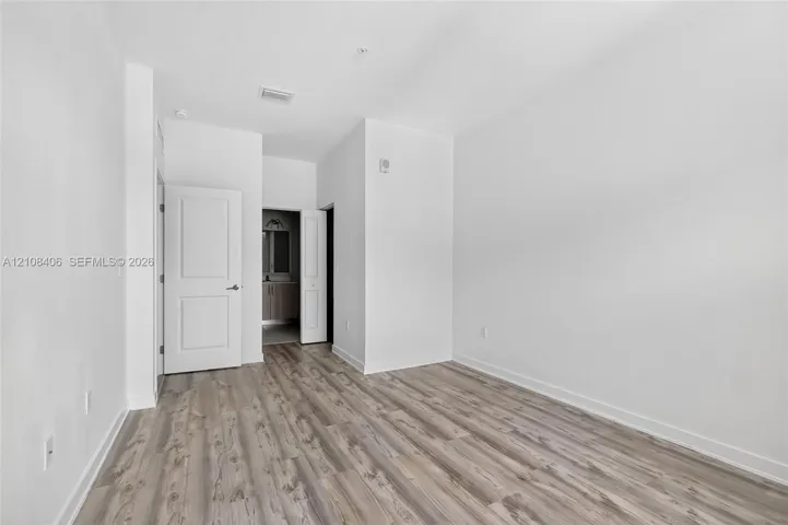 Neutral-toned wood-finish flooring, crisp white walls, and two-panel interior doors