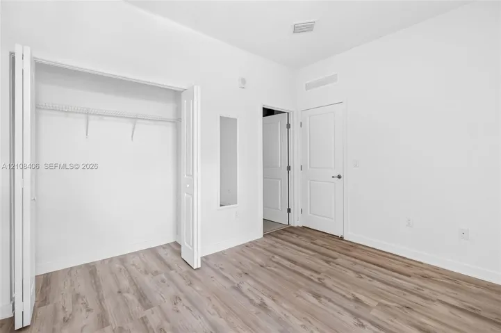 Room featuring wood-finish flooring, a bi-fold closet with built-in wire shelving, and a panel door