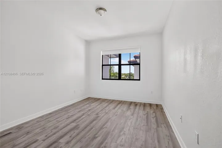 Interior space featuring wood-finish flooring, white walls, and a multi-pane window with black framing