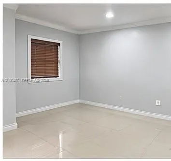 Neutral-toned interior space featuring light-colored tile flooring, crown molding, and recessed lighting