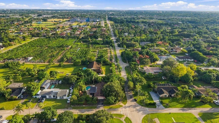 Aerial perspective featuring established residential lots, mature tree canopy, integrated swimming pools, and paved roadways