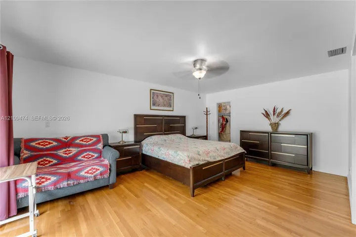 Room featuring wood-finish flooring, a ceiling fan with integrated lighting, and a reach-in closet
