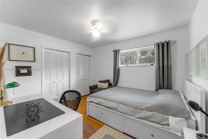 Hardwood flooring, dual louvered-panel closets, and a ceiling-mounted light fixture with integrated fan