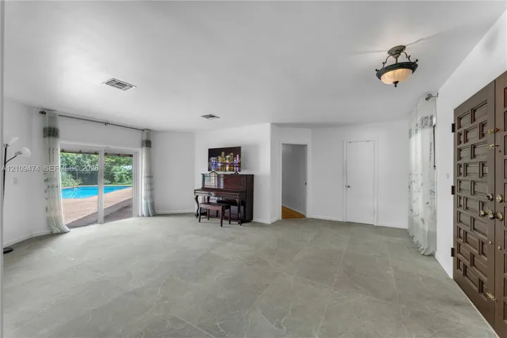 Interior space featuring large-format tile flooring, a custom solid wood multi-panel entry door, recessed lighting, and a sliding glass door providing external access
